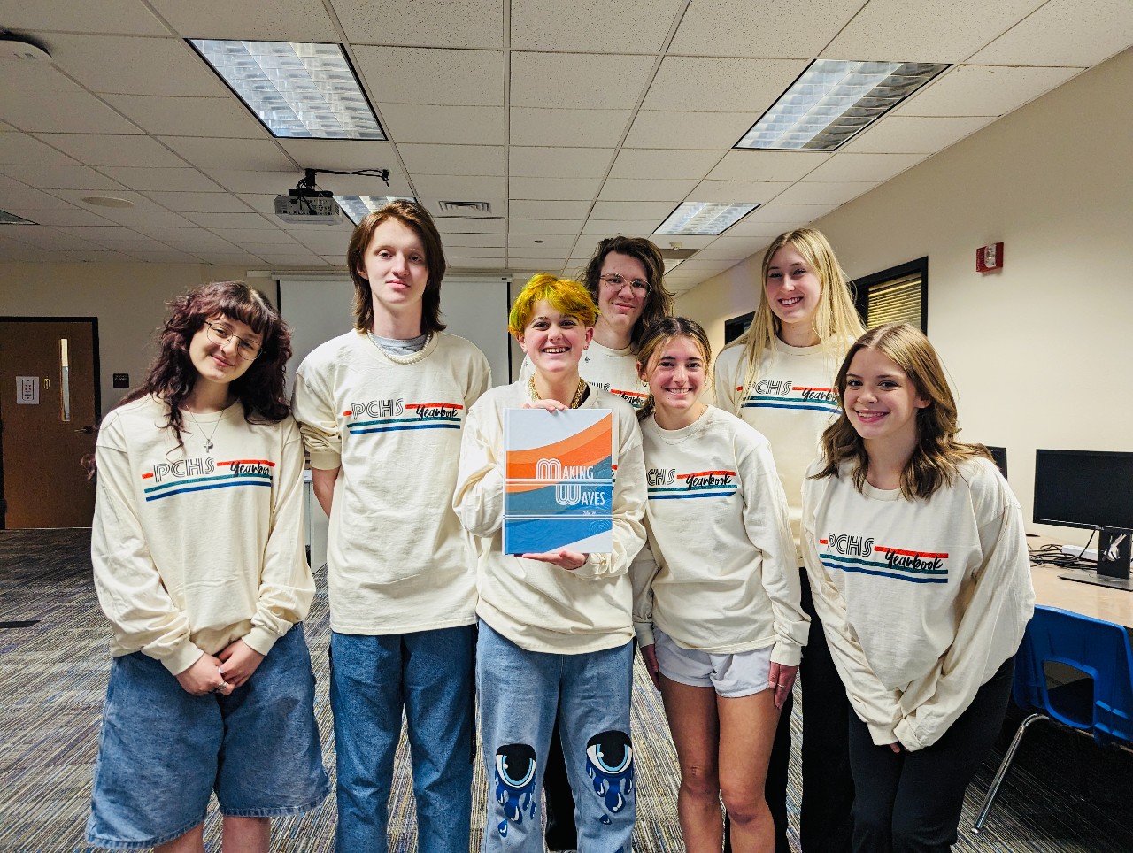 Students holding a copy of this year's Yearbook with the tagline, "Making Waves"